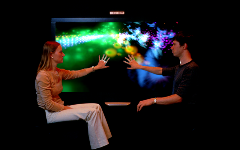 Two people touching an illuminated screen