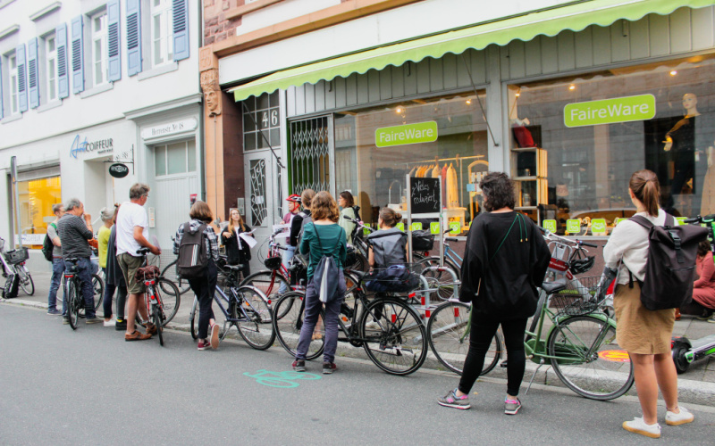 Eine Gruppe Leute versammelt sich mit ihren Fahrrädern vor einem Schaufenster