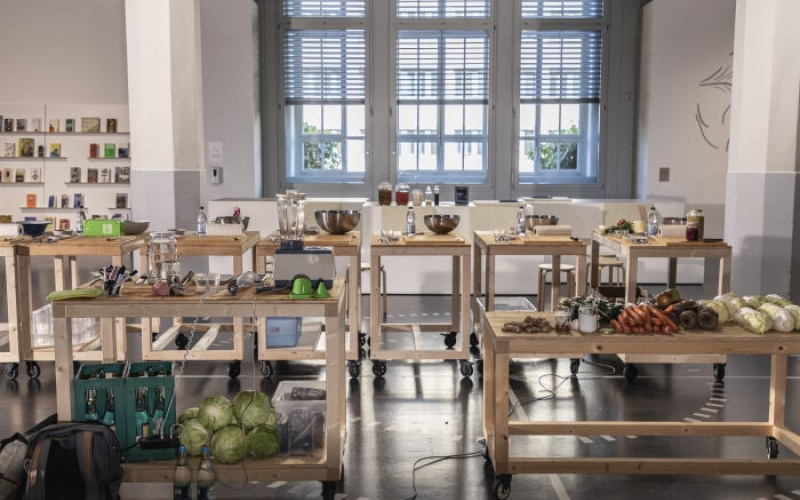 There are wooden tables with food and kitchen tools standing in the ZKM exhibition »Critical Zones«.