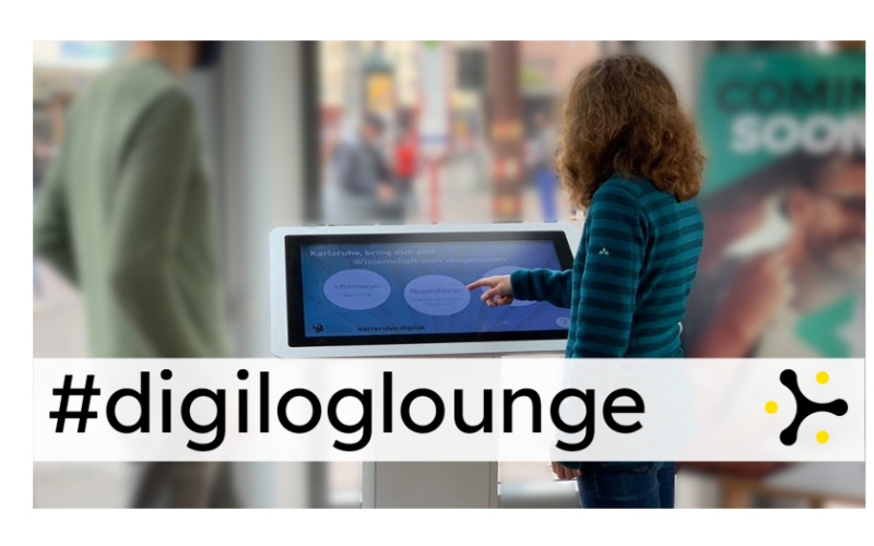 Zwei Personen stehen an einem Panel mit Touchscreen. Über dem Bild liegt das Banner "#digiloglounge"
