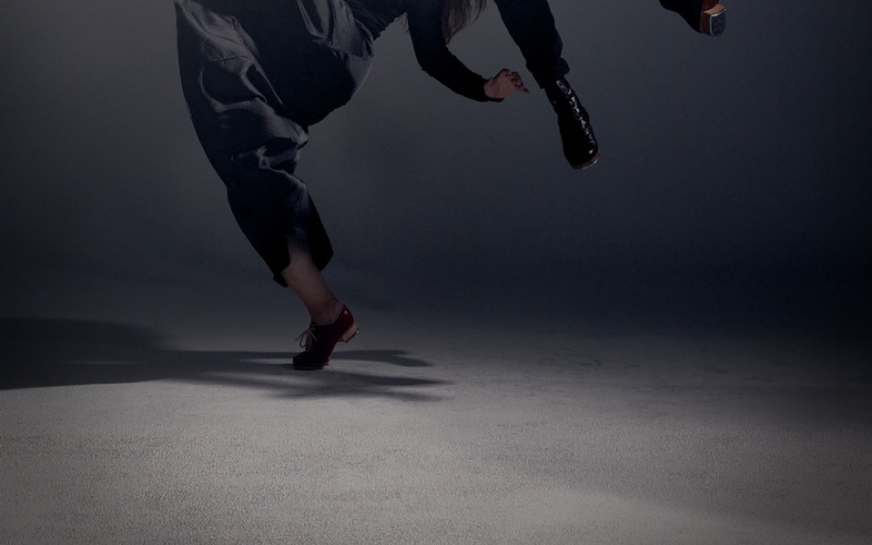 You can see two dancers:inside in black clothes in front of dark gray background