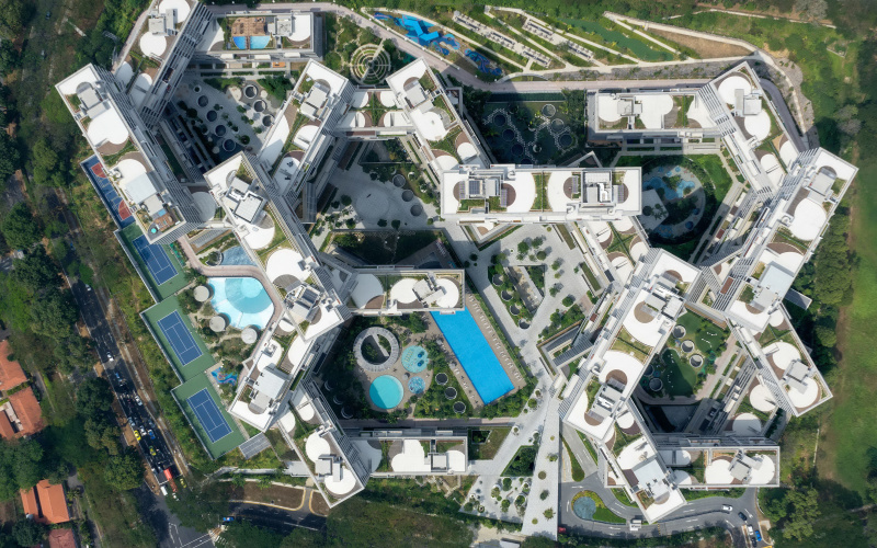 Das Foto zeigt einen großen Gebäudekomplex aus der Vogelperspektive. Von Oben sieht man wie verwinkelt die Stockwerke aufeinander aufbauen und zwischendrin erkennt man viel Grün und Pools.