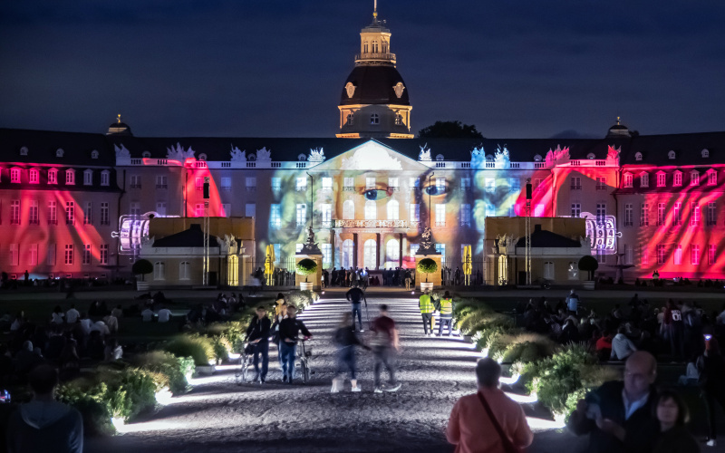 Photo of a colorful projection mapping at night on the baroque Karlsruhe castle.