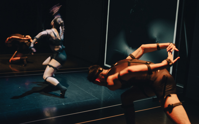 In the photo you can see several (three) dancers moving around the room. The photo has recorded the strong movements. The room in which the dancers are located, is designed completely black and lit only from above with a spotlight. 