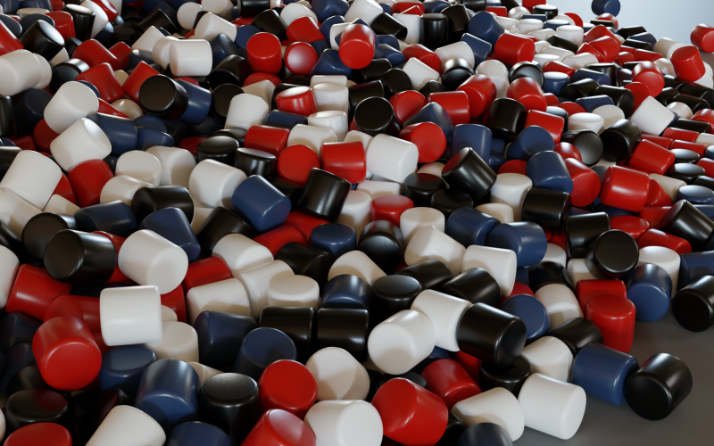The photo depicts many geometric cylinders in red, blue and white colors. They are all lying on a pile.