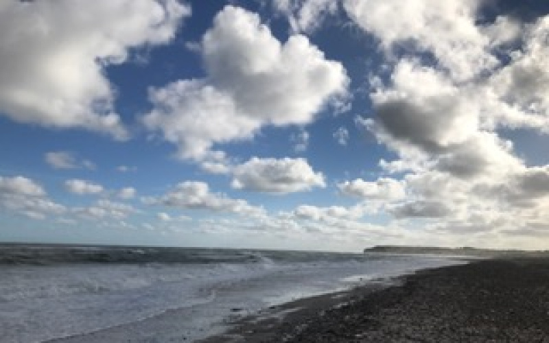 Das Bild zeigt einen Strand unter wolkigem Himmel.