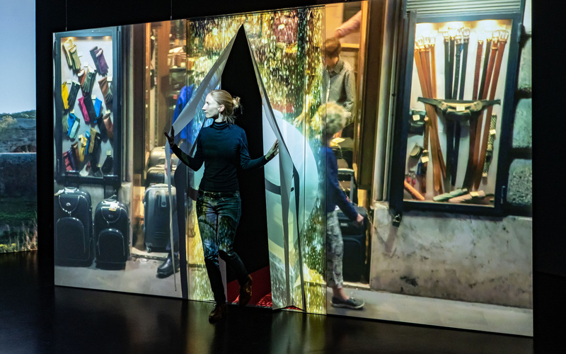 Exhibition view »Marijke van Warmerdam. Then, now, and then«. You can see a person stepping through a curtain on which a video is projected.