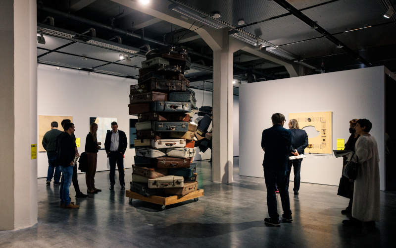 You can see several people standing around a ceiling-high stack of suitcases.