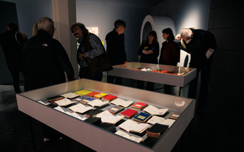 You can see several people gathered around two boxes. In the boxes are several books.