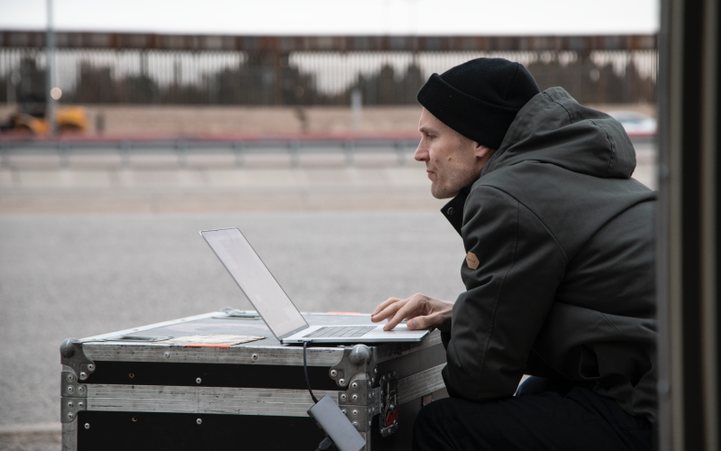 Man sieht Stephan Schulz, der vor einem Laptop sitzt. Dieser steht auf einem schwarzen Koffer.
