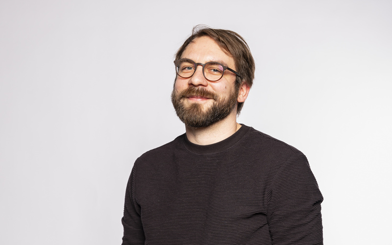 stehender Mann mit schwarzen Hemd und Brille