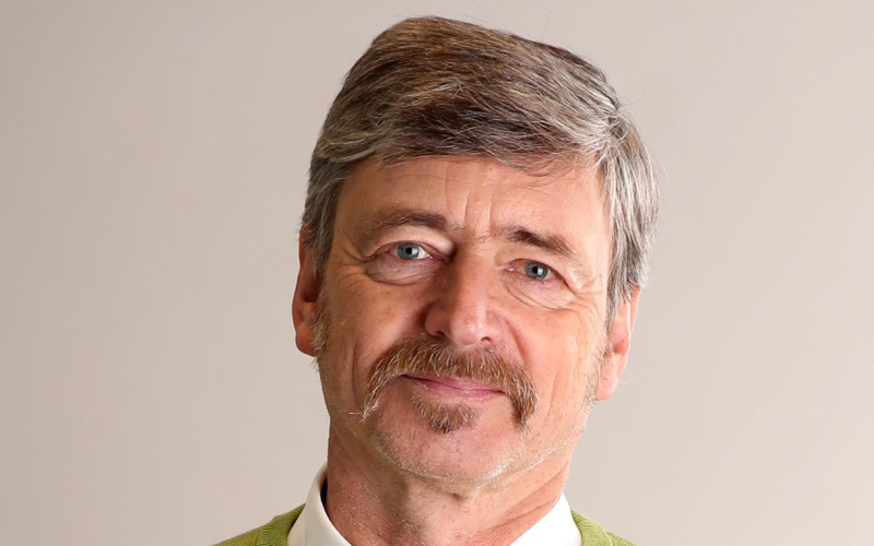 Photo of a man with a moustache wearing a green sweater