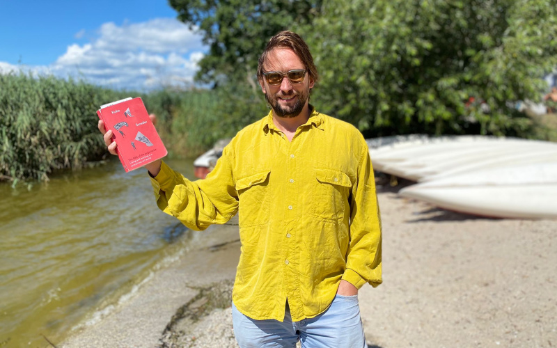 Man in yellow shirt holding a red book