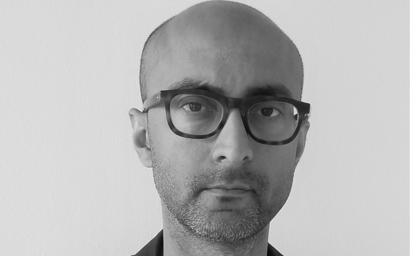 Schwarz-weiß Foto eines Manns mit Brille im Sakko