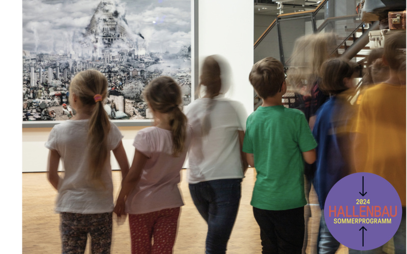 A blurred group of children can be seen in front of a picture showing the Tower of Babel.