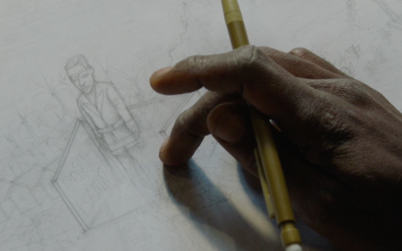 Zu sehen ist eine Detailansicht von einer Hand, die mit einem Stift an einem Bild arbeitet.