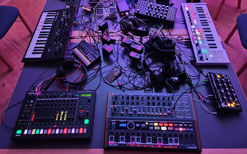Elektronische Synthesizer, Kabel, Keyboards und Lautsprecher auf einem Tisch.