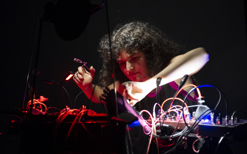 The picture shows a person holding an eyelash curler that is connected to a cable.