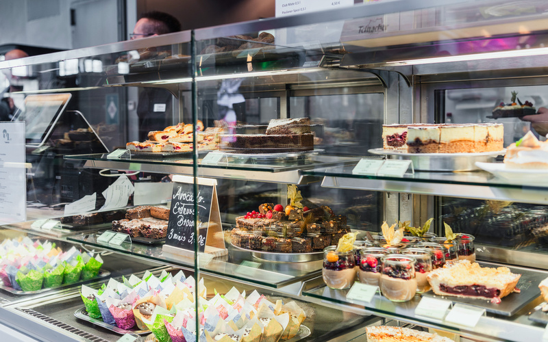 Zu sehen ist eine Theke mit verschiedenen Angeboten wie Kuchen und Muffins. 