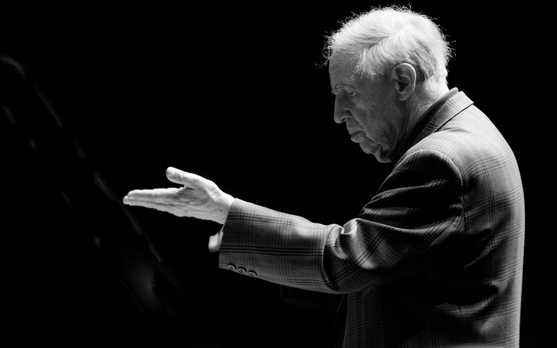 Pierre Boulez in Seitenansicht: Er hebt eine Hand, die Handfläche nach oben.