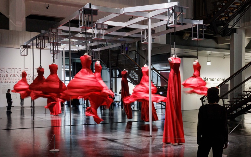 In einer Ausstellungen hängen rote, sich drehende Kleider.