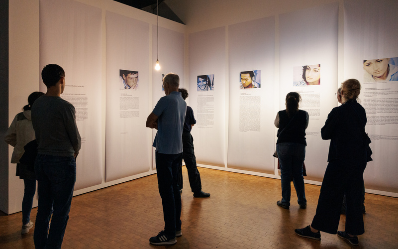 Zu sehen sind Menschen, die Texte in einer Ausstellung lesen.