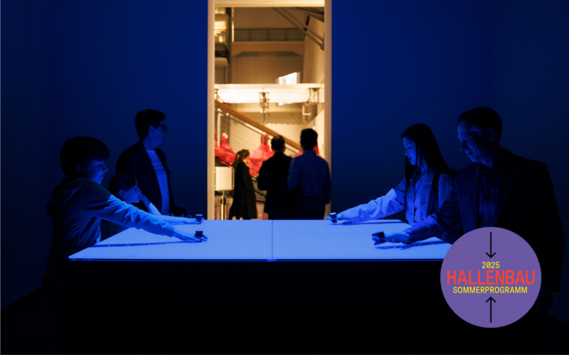 A blue-lit room, four people standing opposite each other at a table.