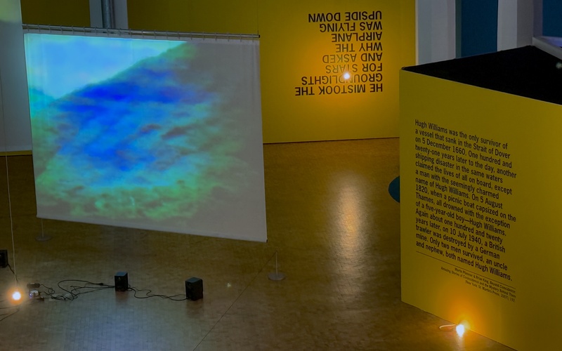 Gelbe Wände und blau-grün beleuchtete Leinwand.