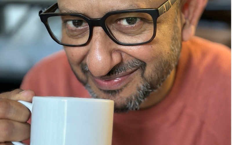 You can see a portrait photo of a person holding a cup in their hand.