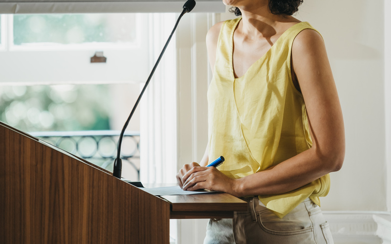 A portrait photograph of a person standing at a lectern.