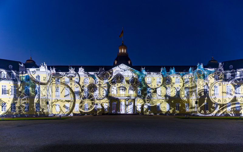 Viele Taschenuhren, die auf das Karlsruher Schloss projiziert werden