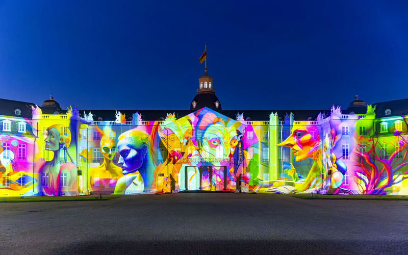 Ein farbenfrohes, KI-generiertes Bild wird auf das Karlsruher Schloss projiziert