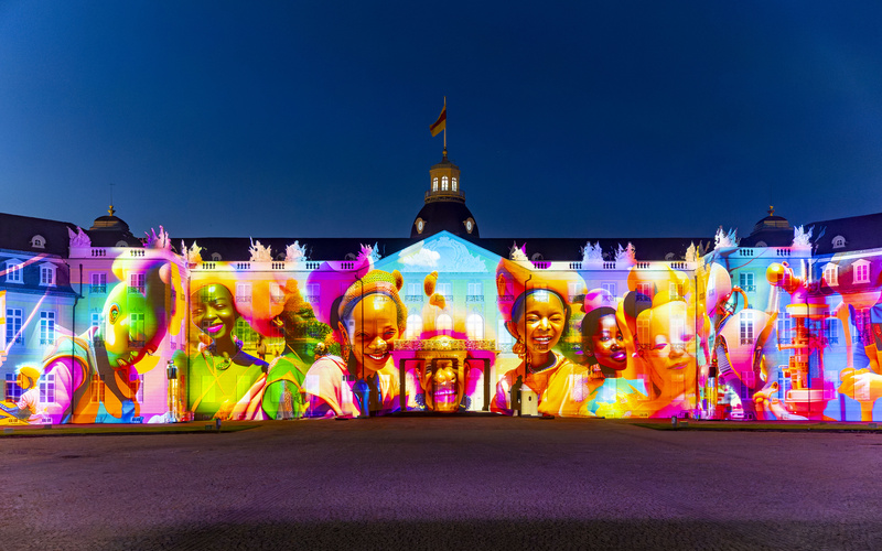 Ein farbenfrohes, KI-generiertes Bild wird auf das Karlsruher Schloss projiziert