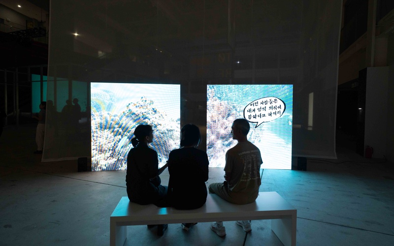 Silhouettes of two people in front of a glowing work of art