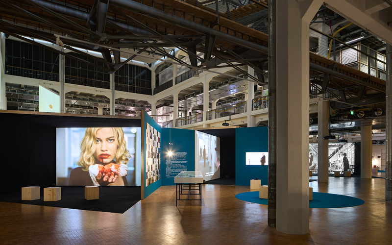 Zu sehen ist ein Ausstellungsraum in dem mehrere Filme gezeigt werden.