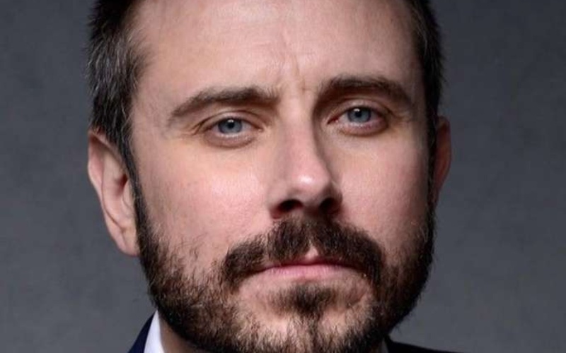 Portrait of a person in front of a grey background.