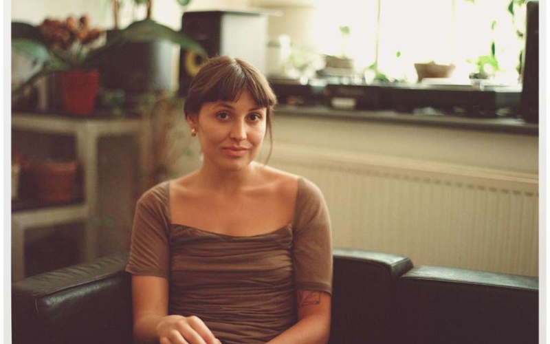 Portraitfoto einer Person auf einem Sofa sitzend.