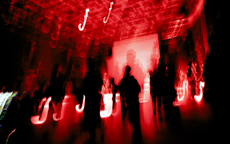 Rote Lichter und die Silhouetten mehrerer Personen sind zu sehen.
