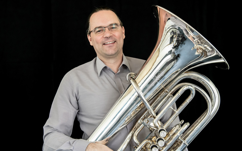 The portrait photo shows a person holding a musical instrument. 