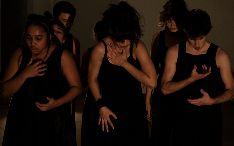 Mehrere Menschen sind stehend zu sehen, während sie eine Tanzperformance aufführen.