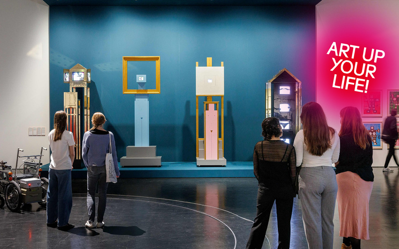 Drei Personen stehen vor einem Kunstwerk.