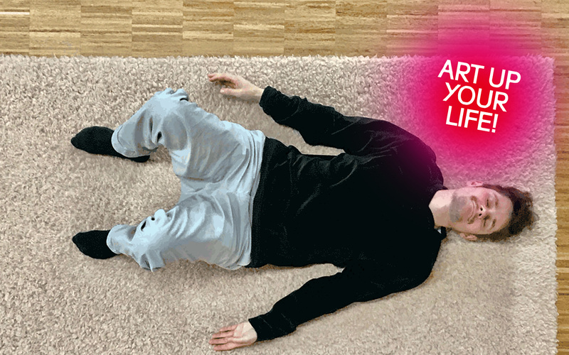 Max Kosoric ist liegend auf einem Teppich von oben zu sehen wie er seine angestellten Beine nach links neigt.