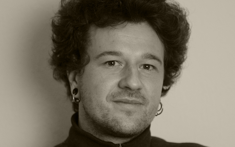 A portrait photo of Arthur Schuman is shown. 