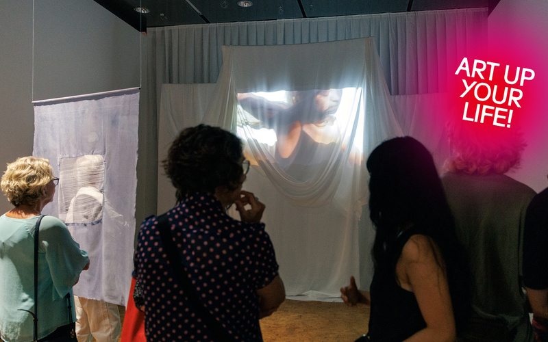 Zu sehen ist sind Besuchende, die eine Projektion betrachten.