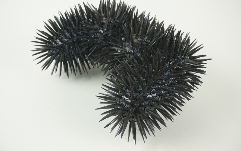 The image shows a video game controller covered in black spikes
