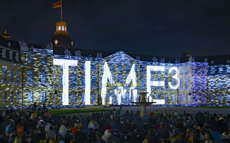 Der Schriftzug "TIME³" wird auf das Karlsruher Schloss projiziert.