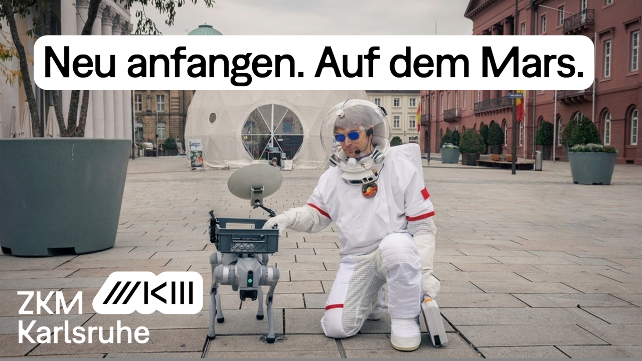 Dan Wilcox im Raumanzug kniet neben einem Roboterhund auf dem Karlsruher Marktplatz.