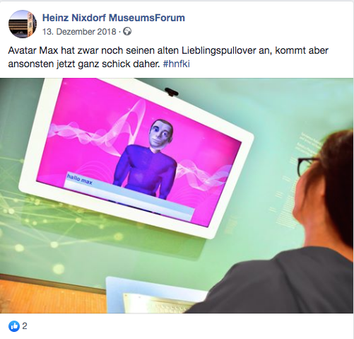 Computergenerierte Person ist auf einem Fernsehbildschirm zu sehen, davor steht eine Museumsbesucherin