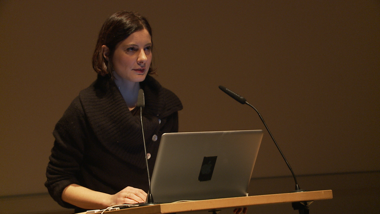 Giulia Vismara steht hinter einem Laptop und hält einen Vortrag.