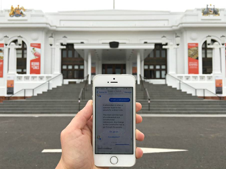 Eine Person mit Smartphone steht vor dem Old Parliament House und nutzt den Chatbot des Museum of Australian Democracy 